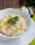Rice and corn in a white bowl garnished with fresh cilantro.