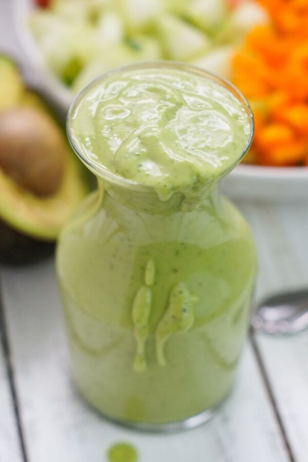 A glass bottle filled with avocado cilantro dressing.