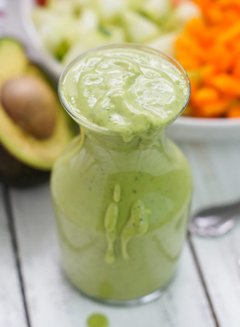 A glass bottle filled with avocado cilantro dressing.