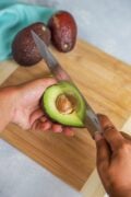 Removing the stone from the avocado with a knife.