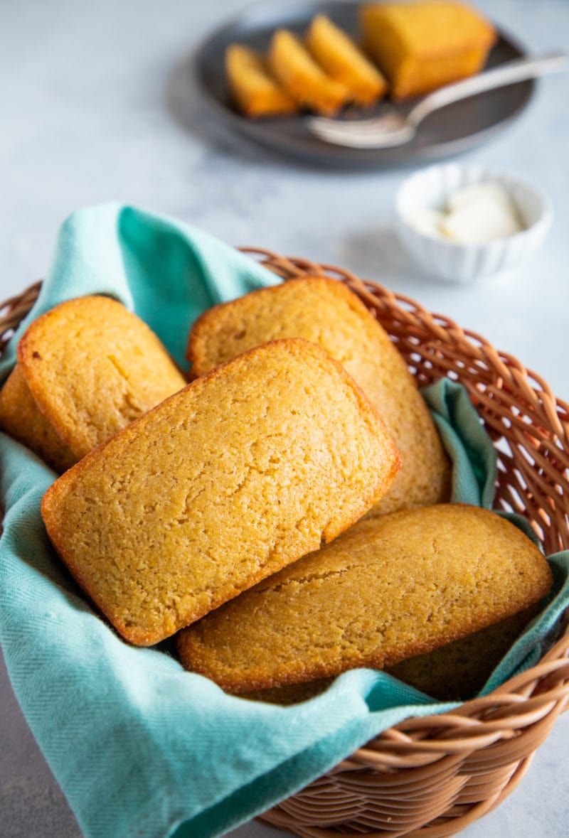 Four cornbread loaves in a basket with a blue cloth.