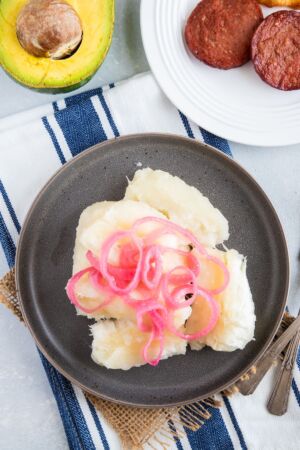Overhead shot of boiled yuca topped with sautéed onions.
