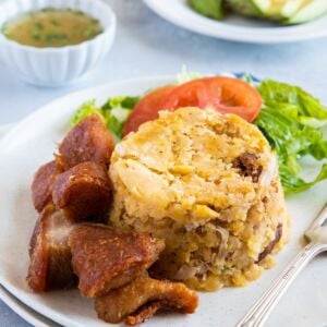 Mofongo served on a plate with a side salad and a fork.
