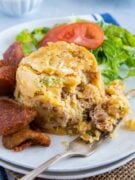 Mofongo servido en un plato blanco con ensalada y chicharrón