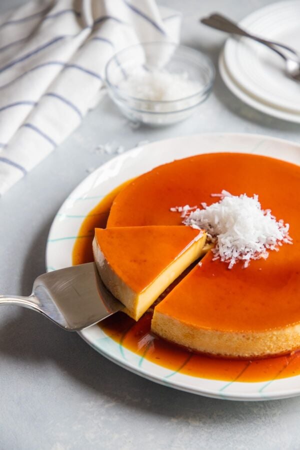 A slice of coconut flan being lifted up on a cake slice.