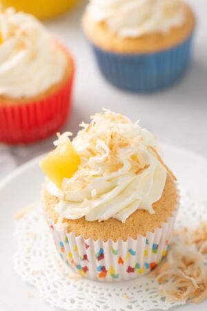 Coconut tres leches cupcake with whipped cream filling and topped with coconut flakes and pineapple