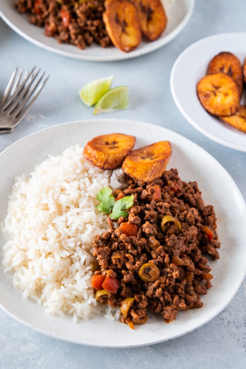 Carne molida de res servida con arroz blanco y platanos maduros fritos en un plato blanco
