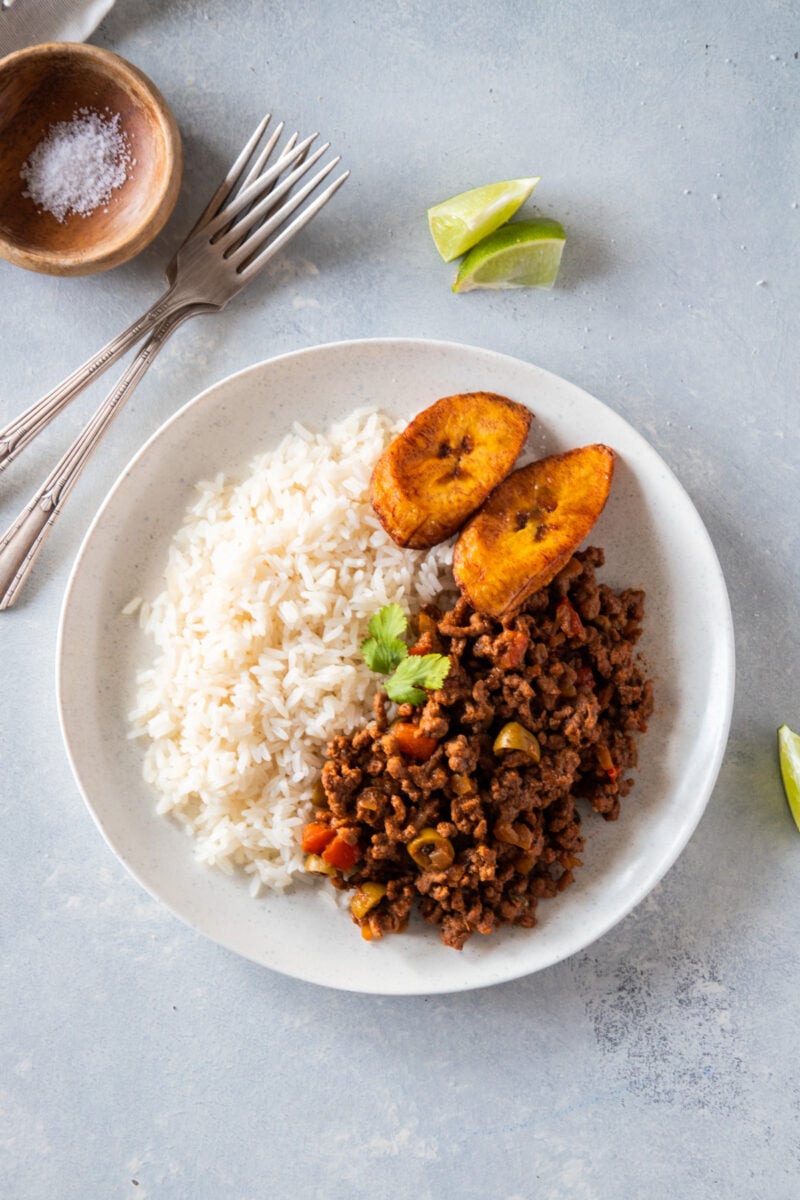 carne molida de res servido en un plato blanco con arroz y platanos maduros fritos