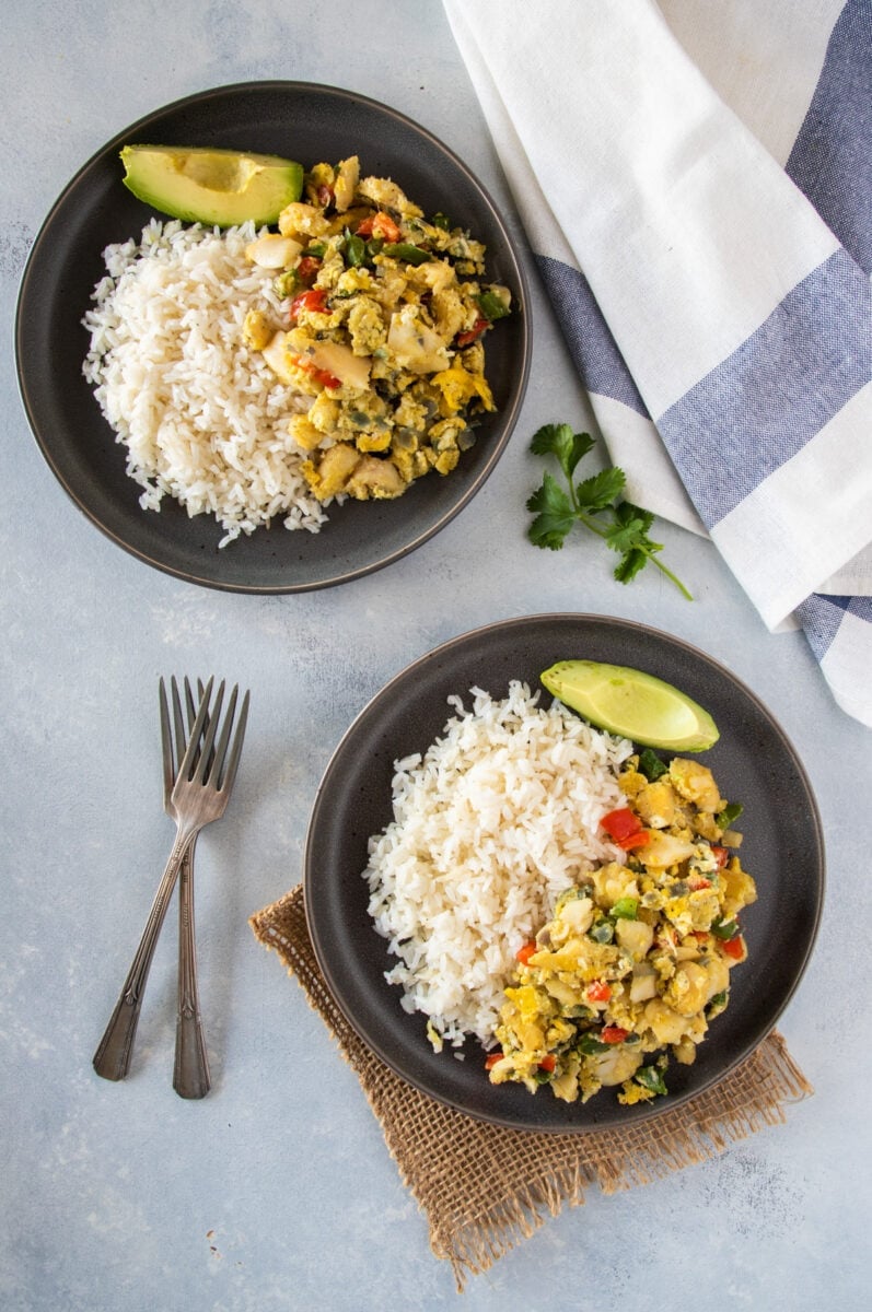 Bacalao con huevos servido con arroz y aguacate al lado.