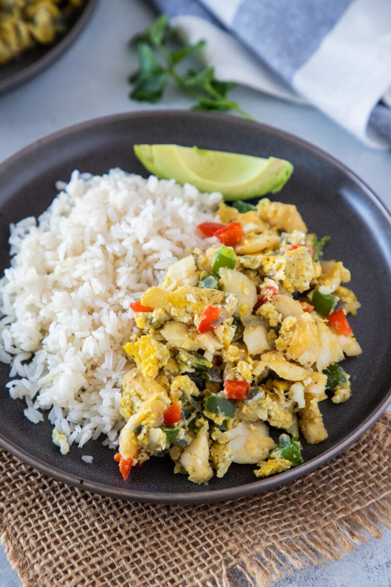 Bacalao con huevos servido con arroz y aguacate al lado.