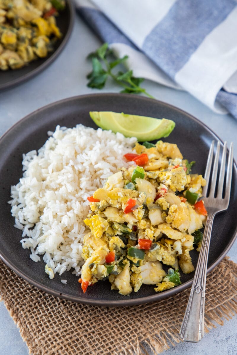 Bacalao con huevos servido con arroz y aguacate al lado.