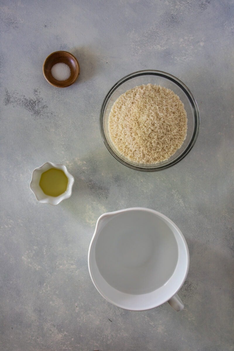 Arroz blanco crudo en un bol con agua, aceite y sal para cocinar.