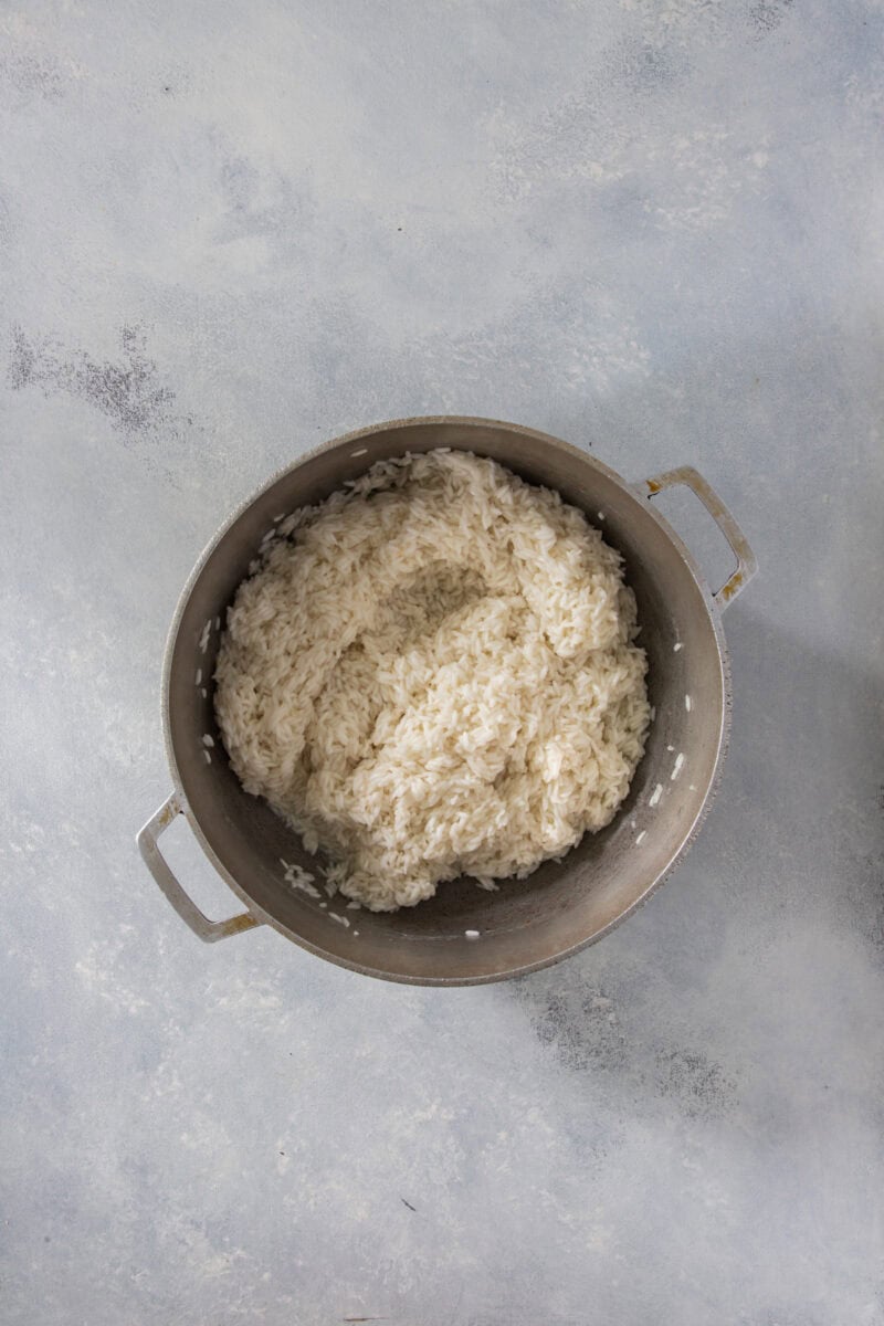 Arroz blanco cocinándose en una olla, con el agua parcialmente absorbida.