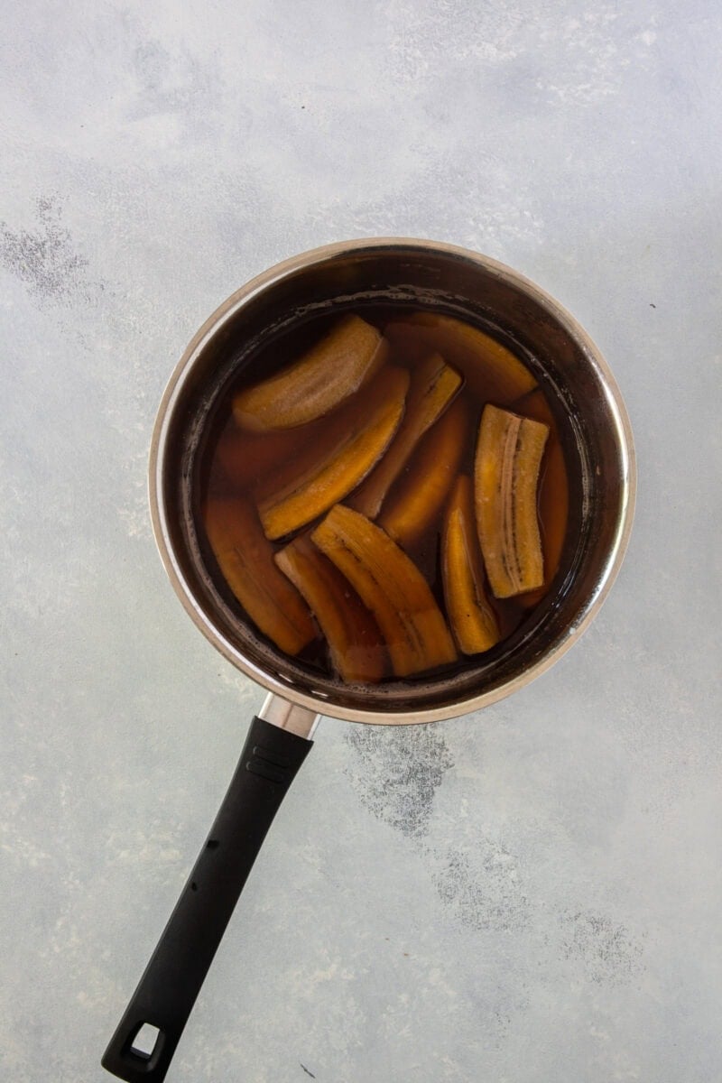 Plátanos verdes pelados y cortados en trozos, en una olla con agua ya cocidos.