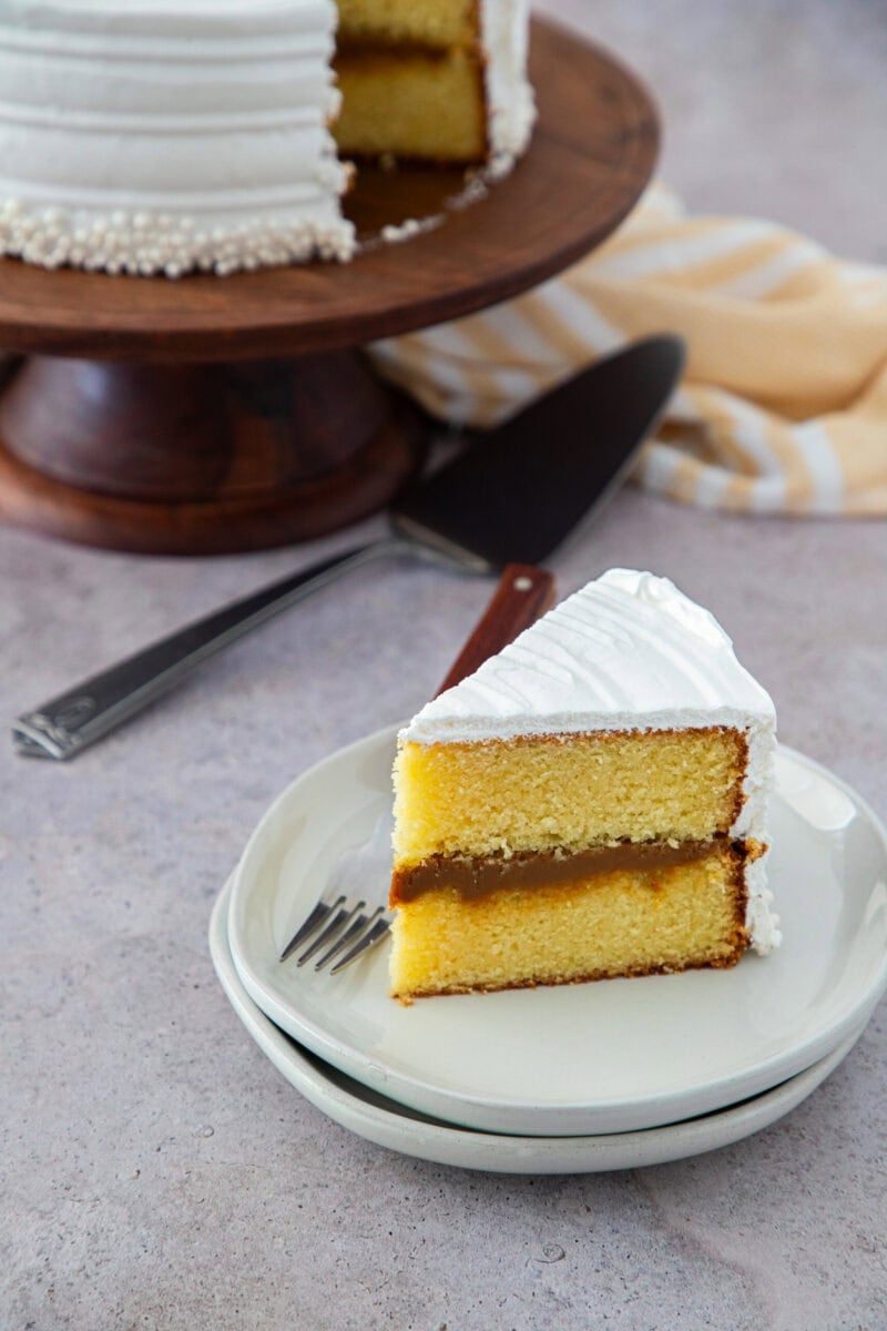 Rebanada de bizcocho dominicano relleno de dulce de leche y cubierto con suspiro blanco, servida en un plato.