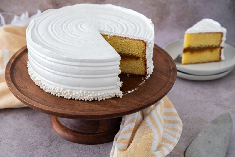 Bizcocho dominicano relleno de dulce de leche y cubierto con suspiro blanco sobre una base de madera.