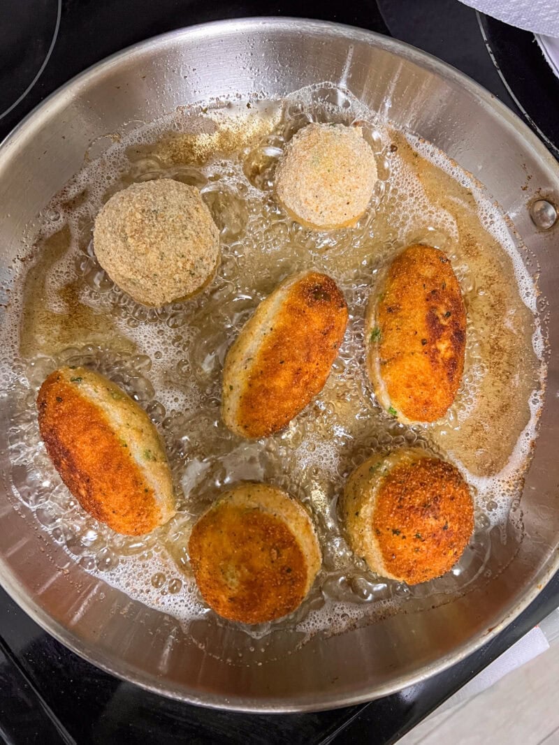 Croquetas de atún y patata friéndose en aceite caliente en una sartén.